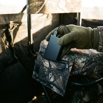 Gloved hand sliding the power bank into the chair's zippered side pocket